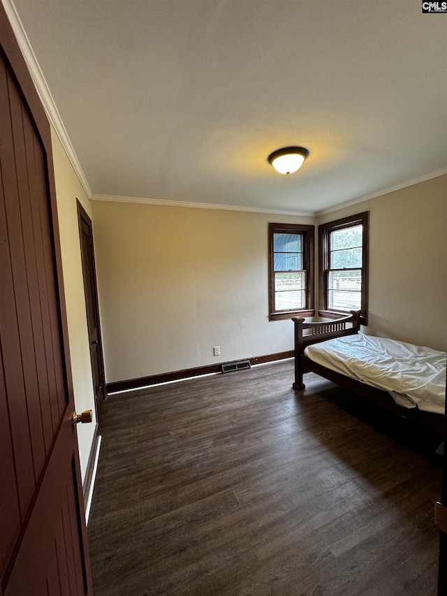 unfurnished bedroom with baseboards, crown molding, visible vents, and dark wood-style flooring