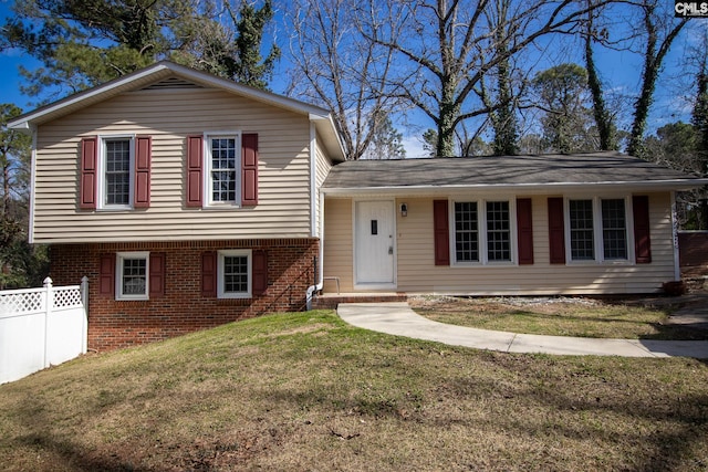 split level home with fence, a front lawn, and brick siding