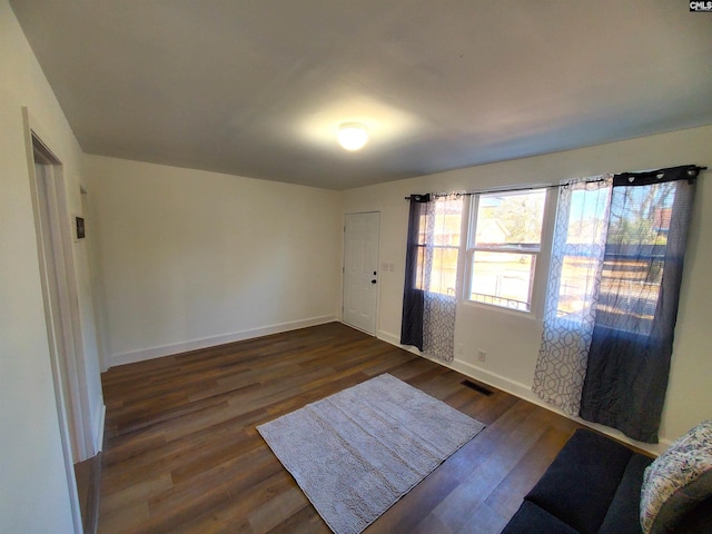 foyer entrance with dark wood-style flooring, visible vents, and baseboards