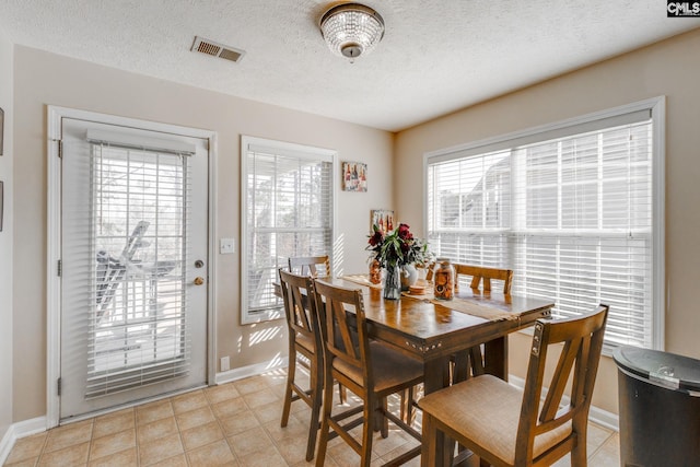 dining room with a textured ceiling, visible vents, and baseboards