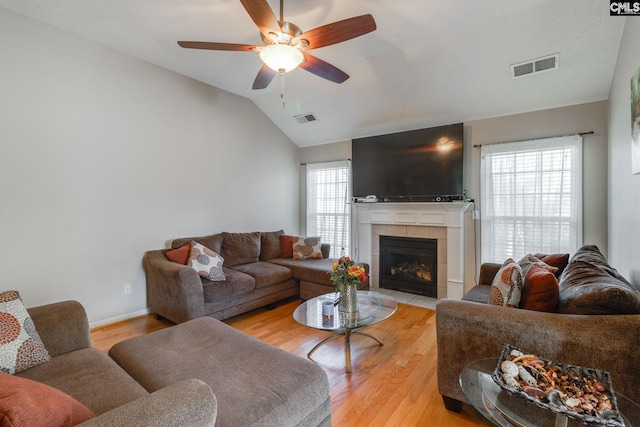 living area with light wood-type flooring, visible vents, a fireplace, and lofted ceiling