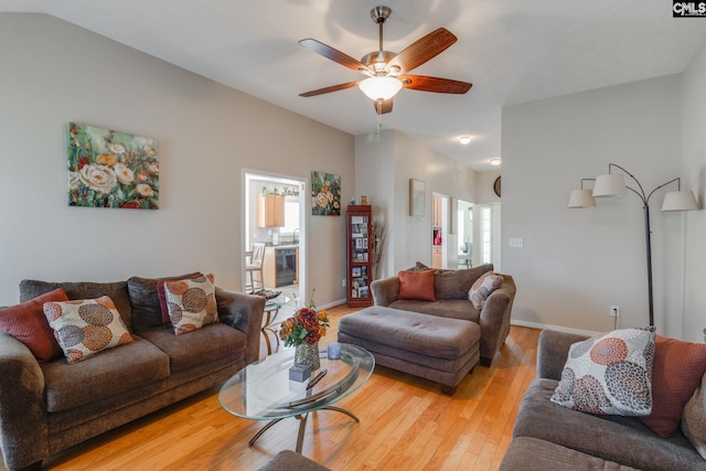 living room with lofted ceiling, light wood finished floors, a ceiling fan, and baseboards