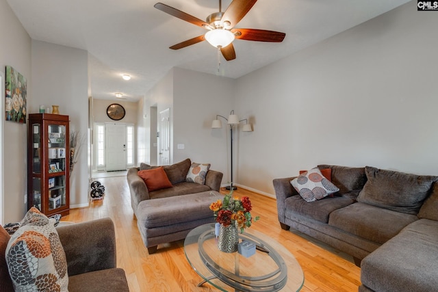 living area with a ceiling fan, baseboards, and wood finished floors