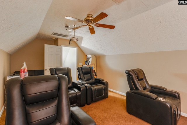 carpeted home theater room featuring lofted ceiling, a textured ceiling, visible vents, and a ceiling fan