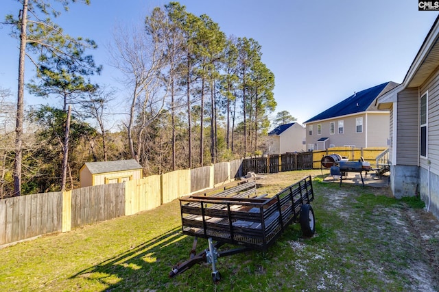 view of yard featuring a storage shed, a fenced backyard, and an outbuilding