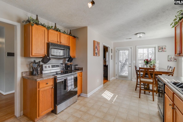 kitchen featuring dark countertops, baseboards, brown cabinets, and black appliances