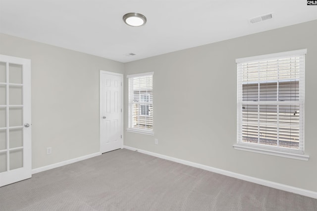 unfurnished room featuring baseboards, visible vents, and light colored carpet