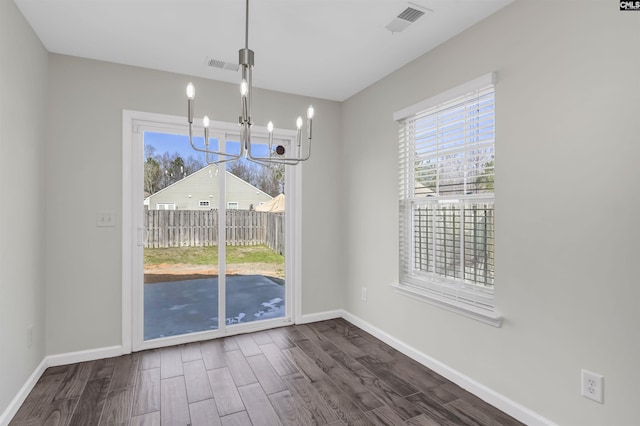 unfurnished dining area with a wealth of natural light, dark wood-style flooring, visible vents, and baseboards