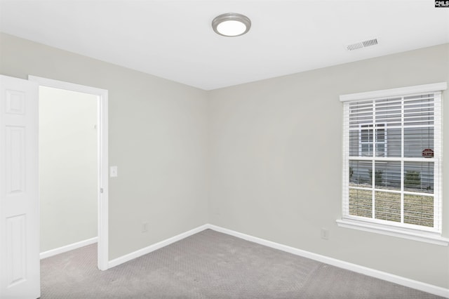 carpeted empty room featuring baseboards and visible vents