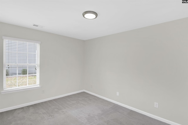 spare room featuring baseboards, visible vents, and carpet flooring