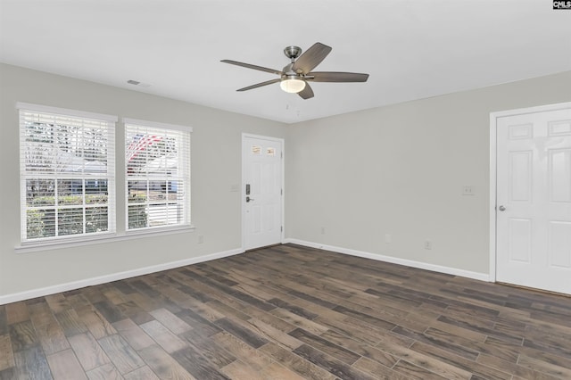 spare room featuring a ceiling fan, visible vents, dark wood finished floors, and baseboards