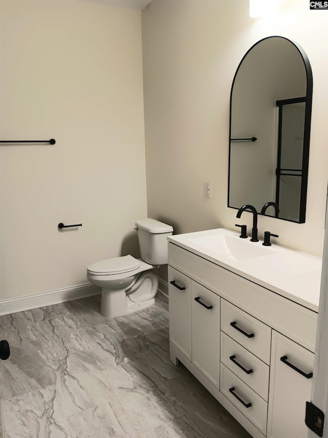 bathroom featuring toilet, marble finish floor, baseboards, and vanity