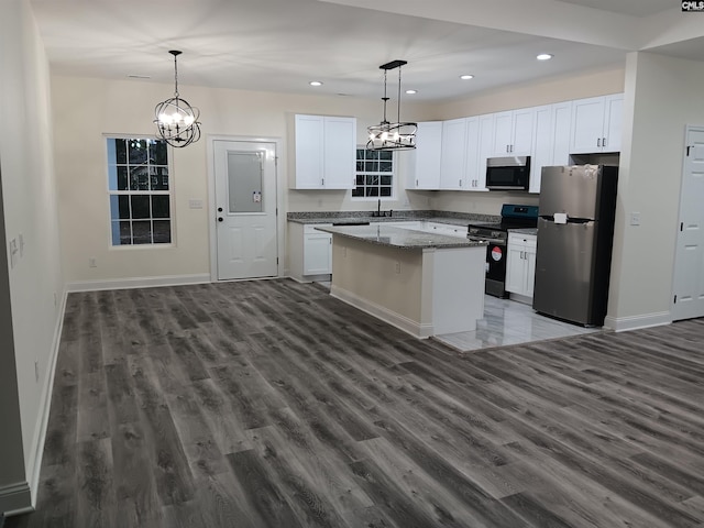 kitchen with pendant lighting, stainless steel appliances, white cabinets, and a center island