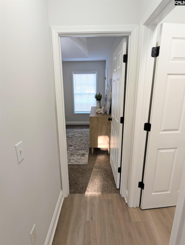 hallway featuring light wood-type flooring and baseboards