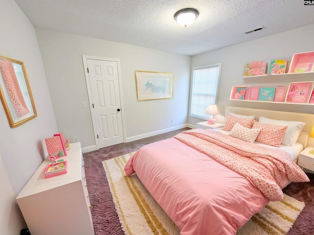 bedroom with a textured ceiling, dark colored carpet, visible vents, and baseboards