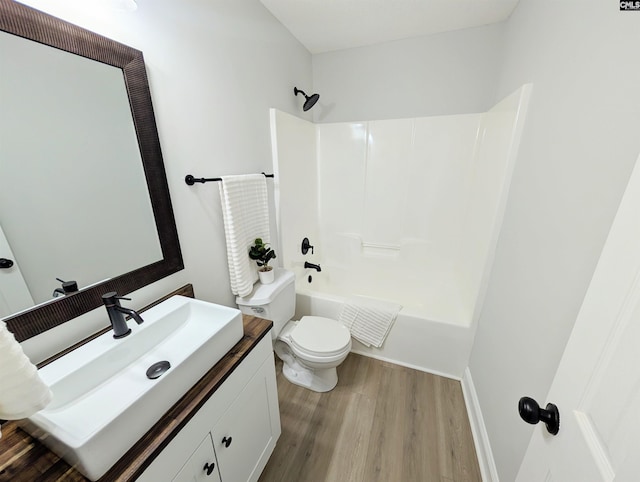 full bathroom featuring toilet, vanity, wood finished floors, and bathing tub / shower combination