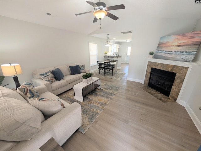 living area with baseboards, light wood-style flooring, visible vents, and a ceiling fan