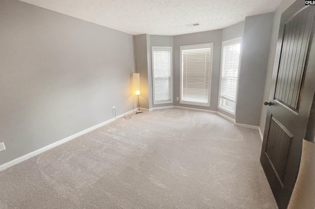 spare room featuring baseboards, visible vents, and a wealth of natural light