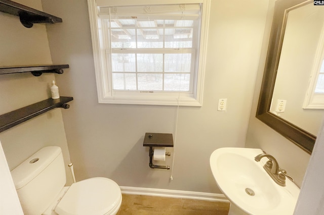 bathroom featuring baseboards, a sink, and toilet