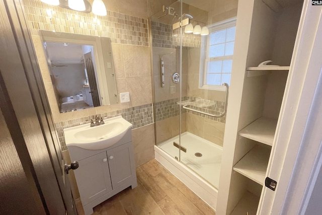 full bathroom with wood finished floors, vanity, tile walls, decorative backsplash, and a stall shower