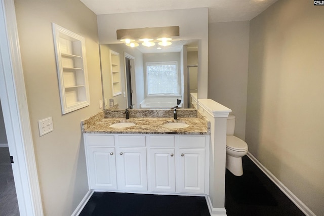 bathroom featuring built in shelves, a sink, and baseboards