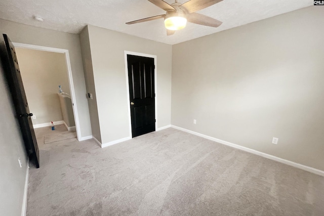 unfurnished bedroom featuring carpet floors, a textured ceiling, baseboards, and a ceiling fan