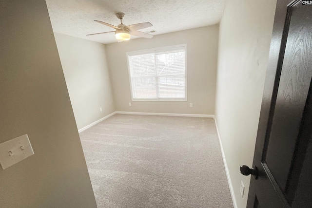 unfurnished room featuring a textured ceiling, baseboards, and light colored carpet