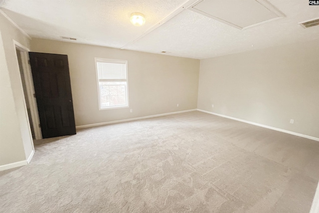 spare room featuring light carpet, a textured ceiling, visible vents, and baseboards