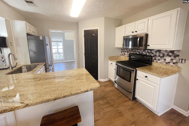 kitchen with stainless steel appliances, white cabinetry, a sink, and visible vents