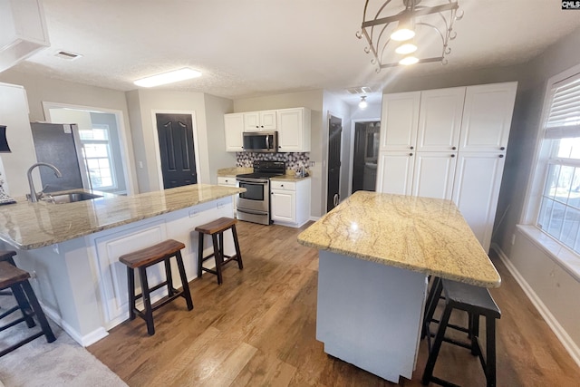 kitchen with light wood-type flooring, visible vents, appliances with stainless steel finishes, and a breakfast bar area