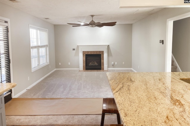 unfurnished living room with ceiling fan, a fireplace, visible vents, baseboards, and carpet