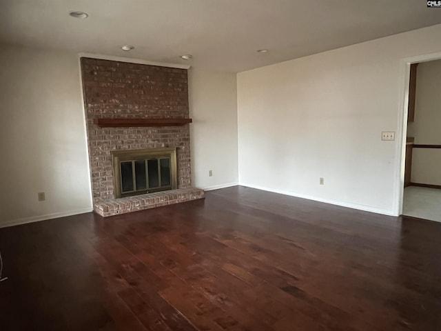 unfurnished living room with dark wood-type flooring, a fireplace, and baseboards