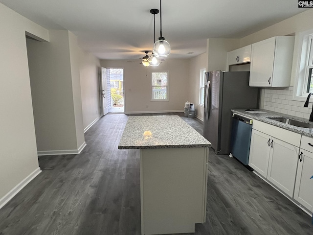 kitchen with light stone counters, a sink, white cabinets, a center island, and dishwasher