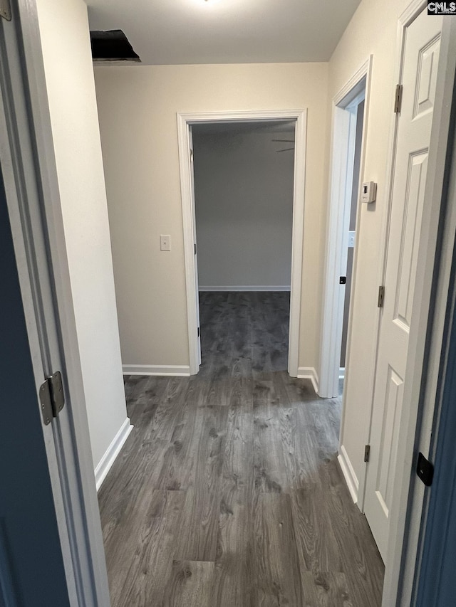 corridor with dark wood finished floors and baseboards