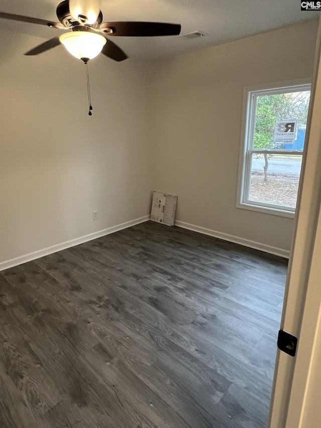 spare room featuring a ceiling fan, dark wood-style flooring, visible vents, and baseboards