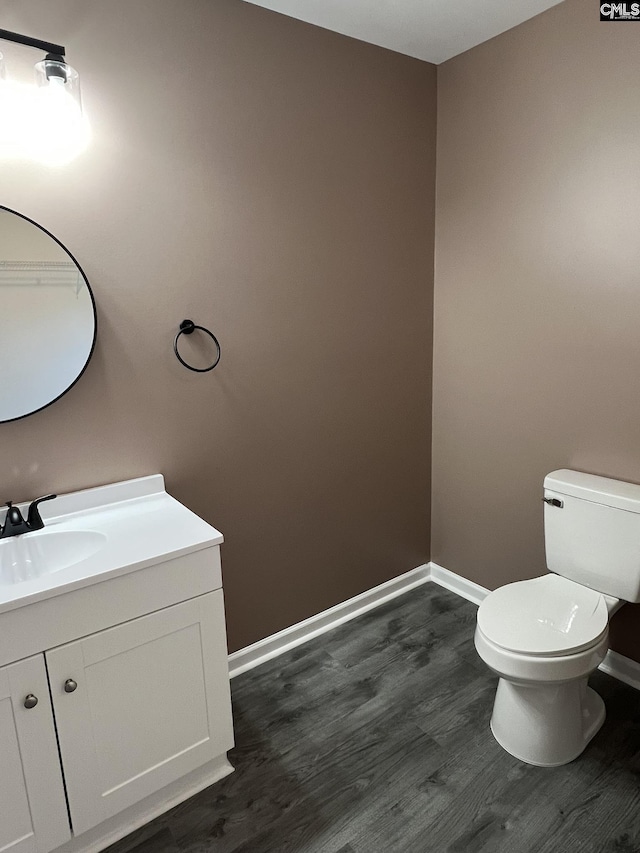 bathroom with toilet, baseboards, wood finished floors, and vanity