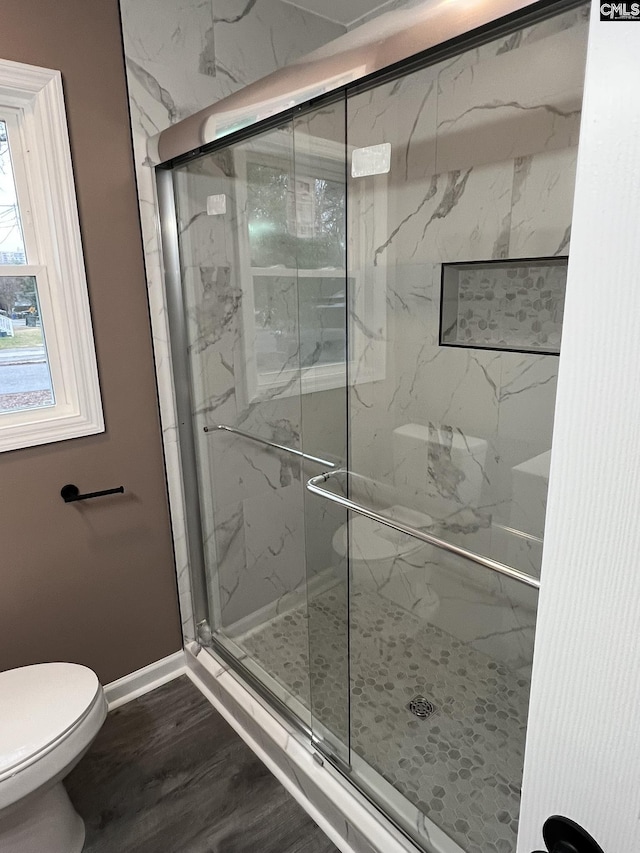 bathroom featuring a stall shower, toilet, baseboards, and wood finished floors