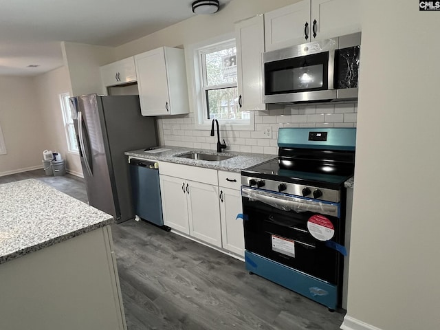 kitchen featuring appliances with stainless steel finishes, white cabinets, a sink, and light stone counters