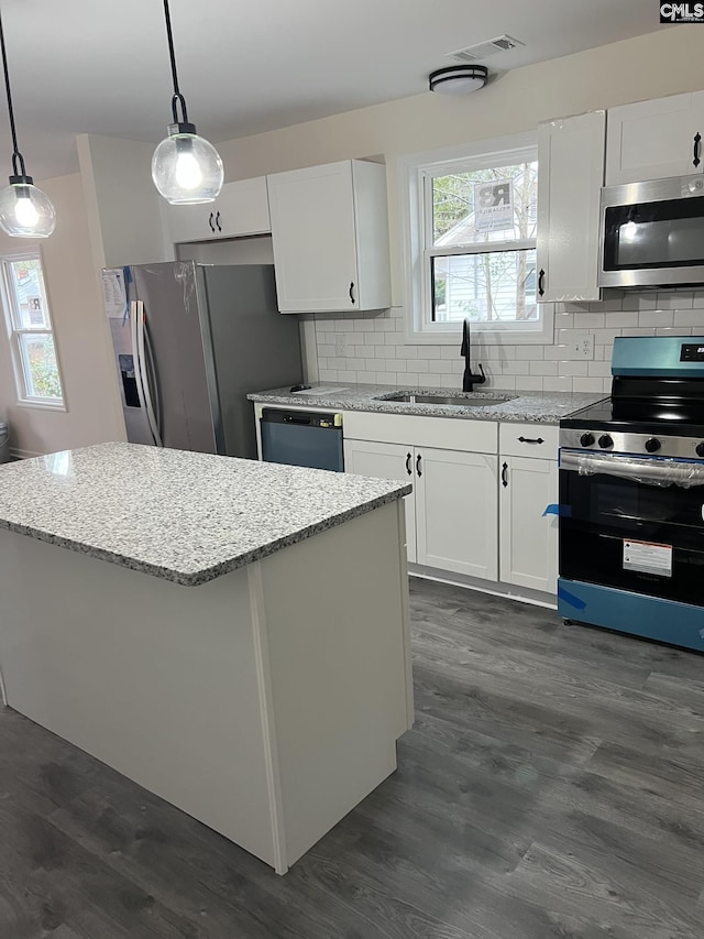 kitchen featuring stainless steel appliances, white cabinets, a sink, and decorative light fixtures