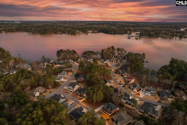 aerial view at dusk featuring a residential view and a water view