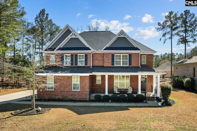 view of front facade featuring a front yard, covered porch, and brick siding