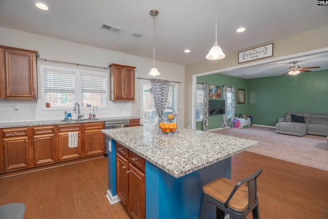 kitchen with a sink, visible vents, open floor plan, a center island, and decorative light fixtures