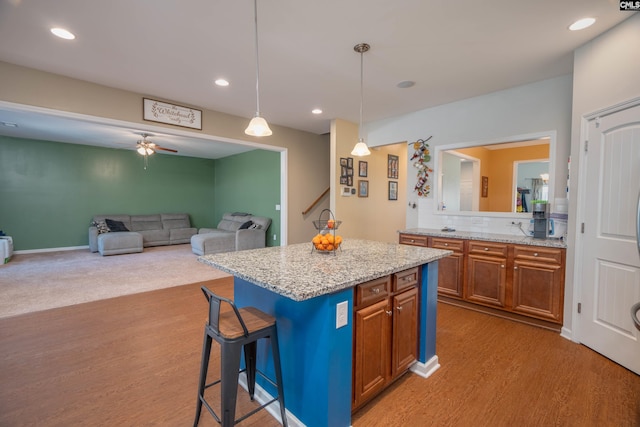 kitchen with a breakfast bar, brown cabinets, decorative light fixtures, open floor plan, and a kitchen island