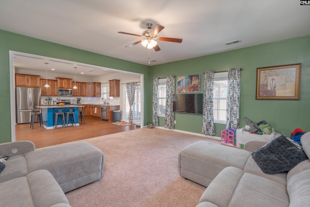 living room with baseboards, visible vents, and a ceiling fan