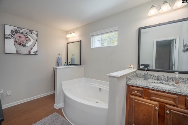 bathroom featuring wood finished floors, a garden tub, vanity, and baseboards