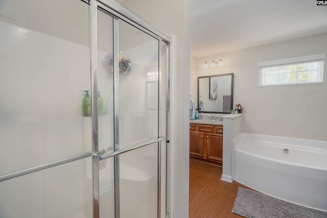 bathroom featuring wood finished floors, a stall shower, a garden tub, and vanity