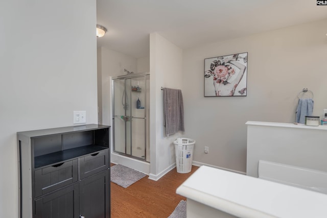 bathroom featuring a shower stall, baseboards, and wood finished floors