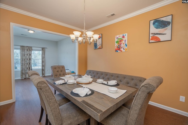 dining space with baseboards, visible vents, dark wood-style floors, ornamental molding, and a notable chandelier