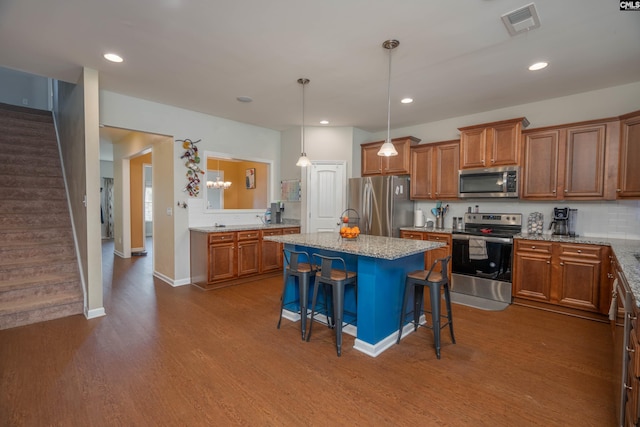 kitchen with appliances with stainless steel finishes, a breakfast bar area, a kitchen island, and brown cabinets