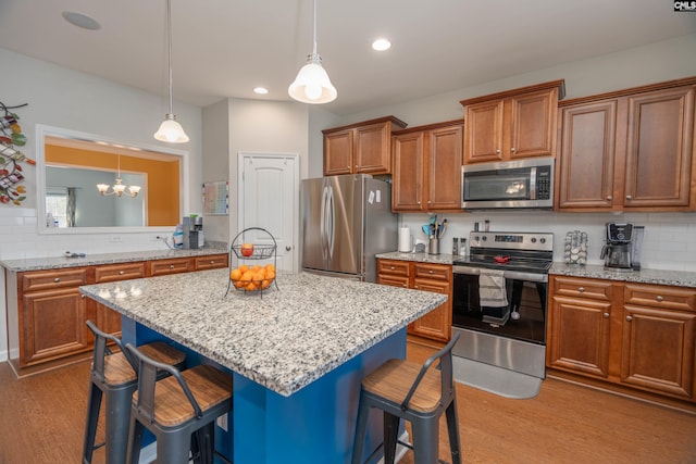 kitchen with stainless steel appliances, brown cabinets, a kitchen island, and a kitchen bar